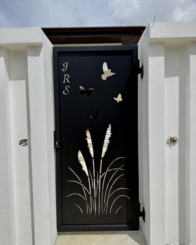 A pedestrian gate with initials, butterflies and reeds cut through the steel