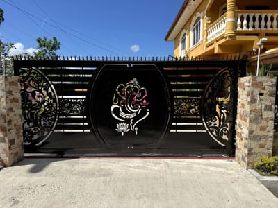 A driveway gate with a Ganesha medallion cut through the steel